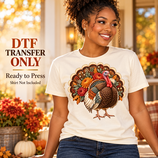Woman wearing a cream shirt with a detailed turkey, layered tail feathers, and autumn flowers on a fall porch.