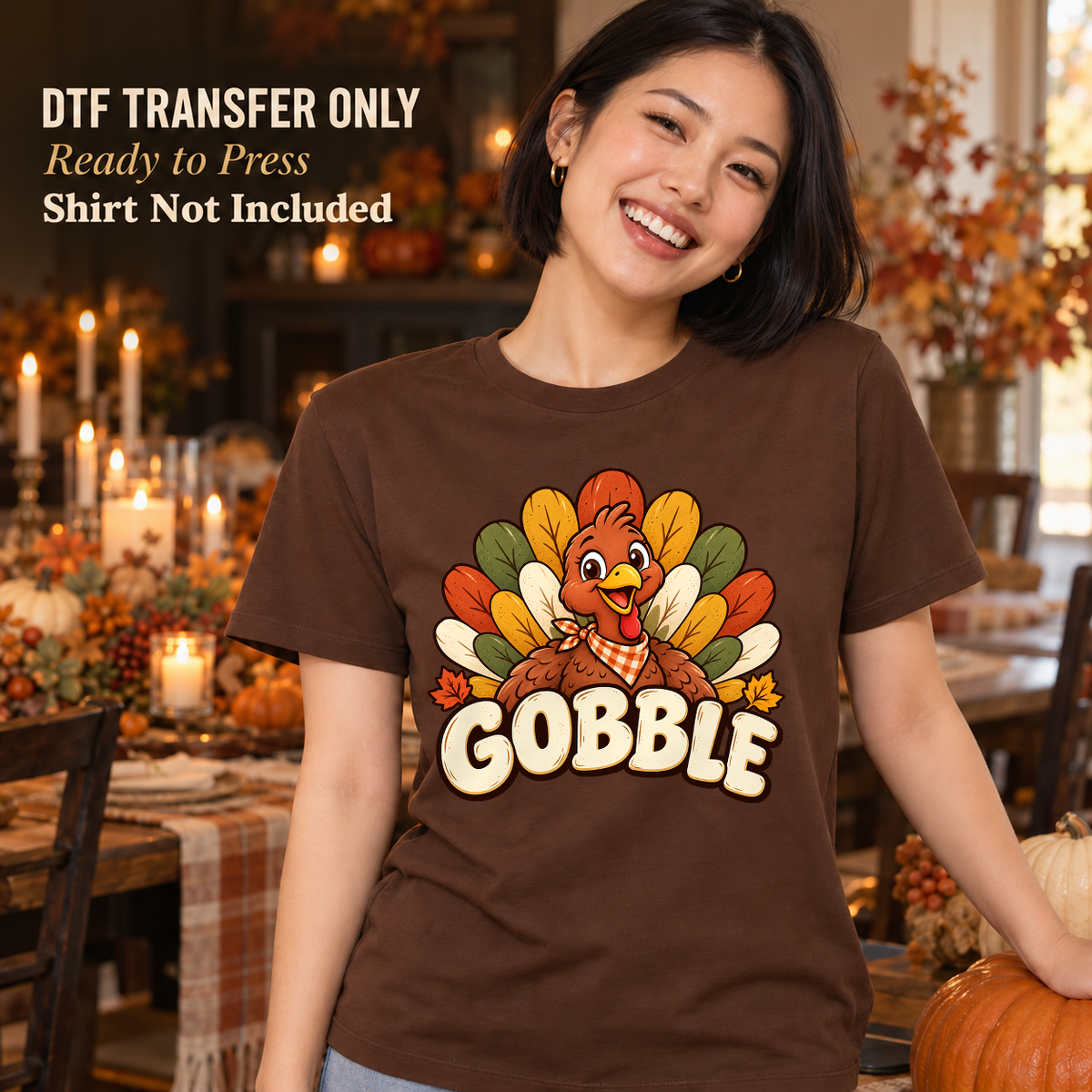Woman wearing a brown shirt with a smiling cartoon turkey and large cream Gobble lettering in a fall dining room.