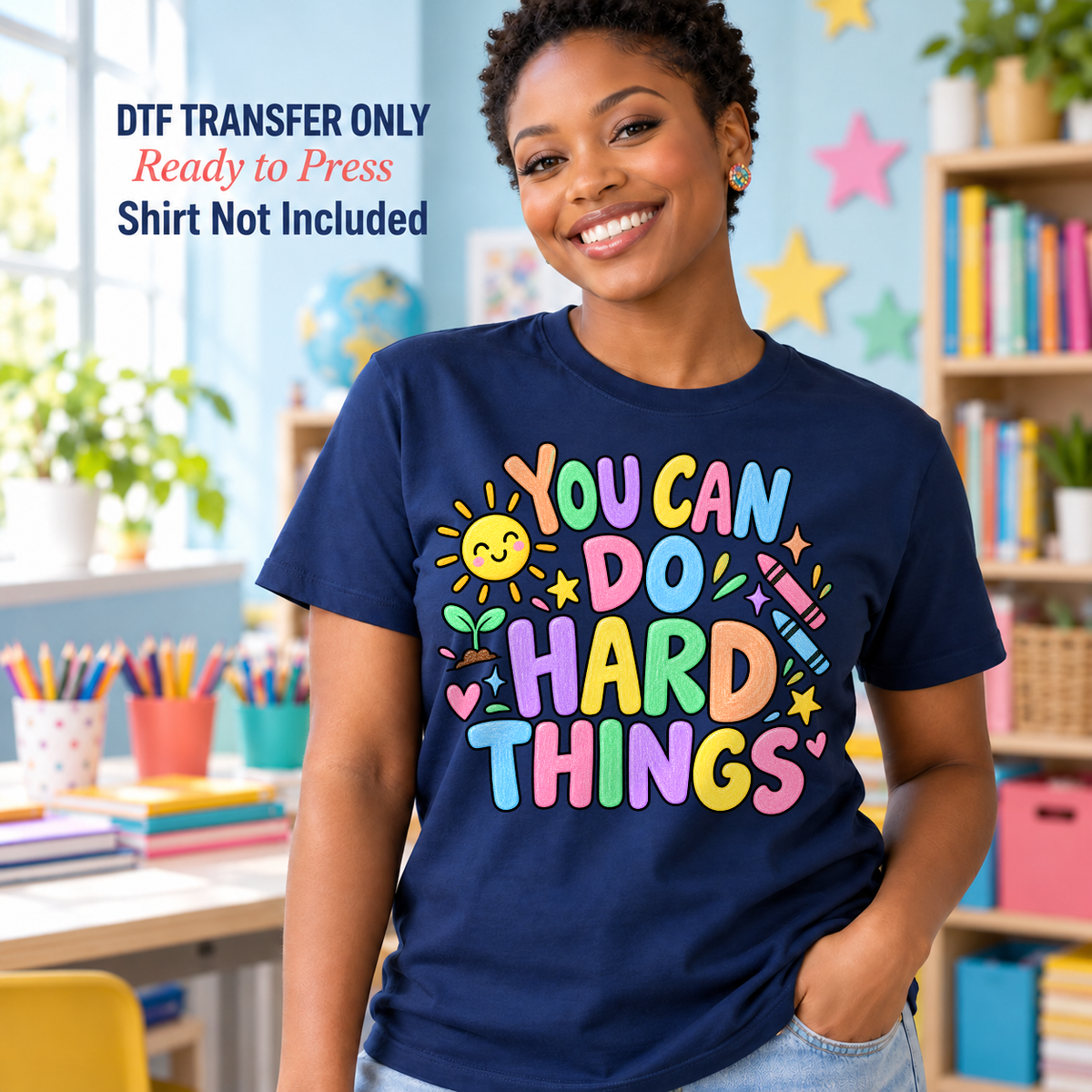 Woman in a navy shirt with colorful You Can Do Hard Things lettering, a smiling sun, and school accents in a classroom.