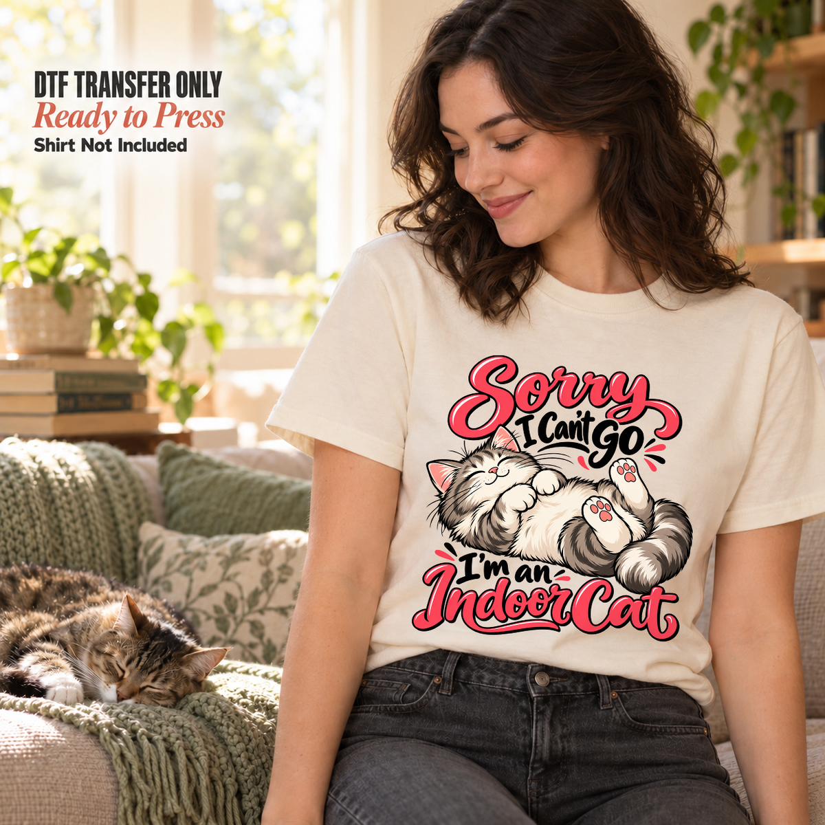 Woman wearing a cream shirt with a lounging kitten and Sorry I Can't Go I'm an Indoor Cat lettering in a living room.