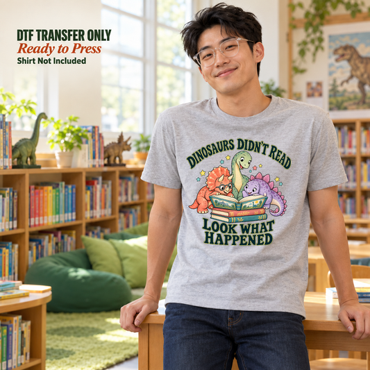 Man wearing a grey shirt with book-reading cartoon dinosaurs and Dinosaurs Didn't Read Look What Happened lettering in a library.