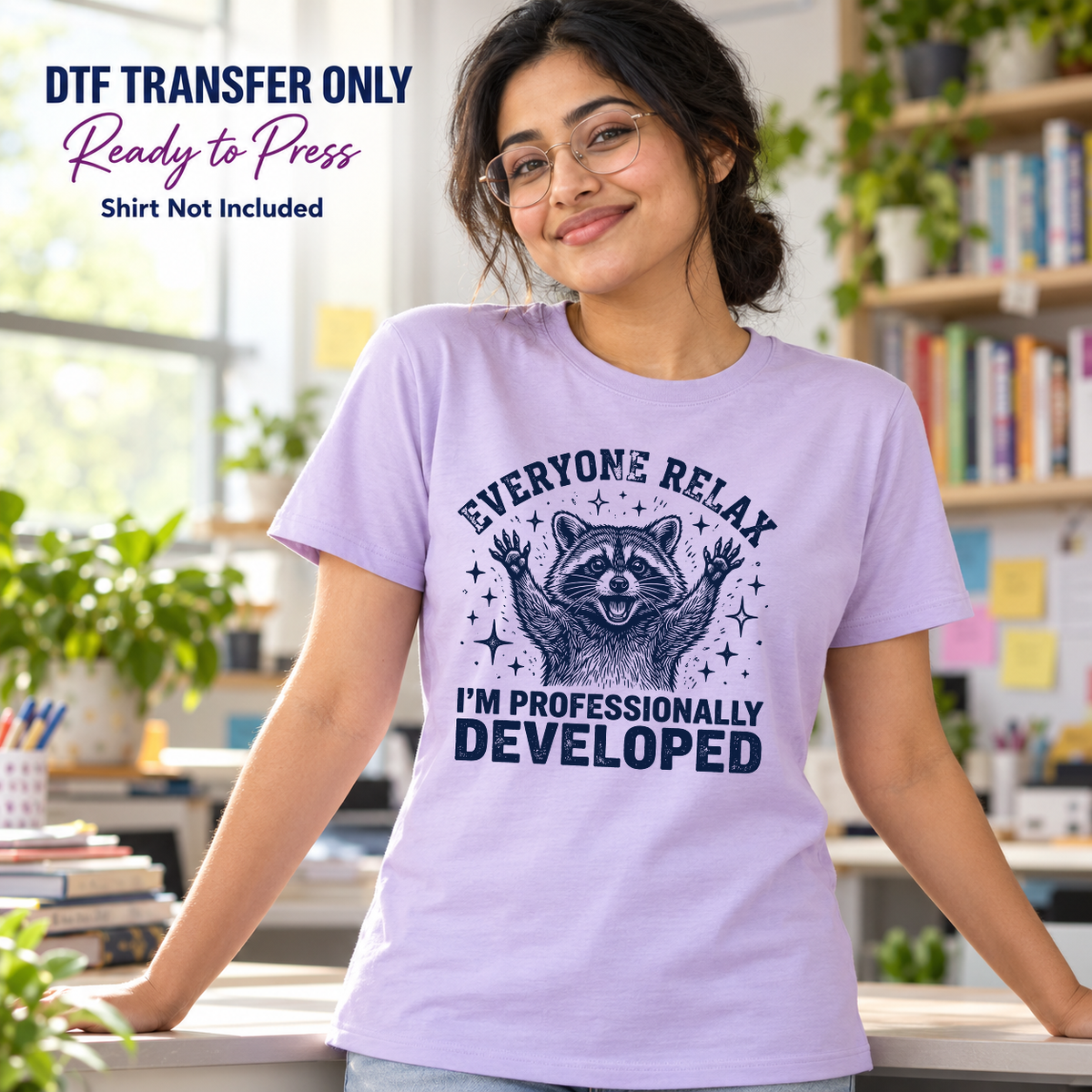 Woman in a lavender shirt with a raised-paw raccoon and Everyone Relax I'm Professionally Developed lettering in a classroom.