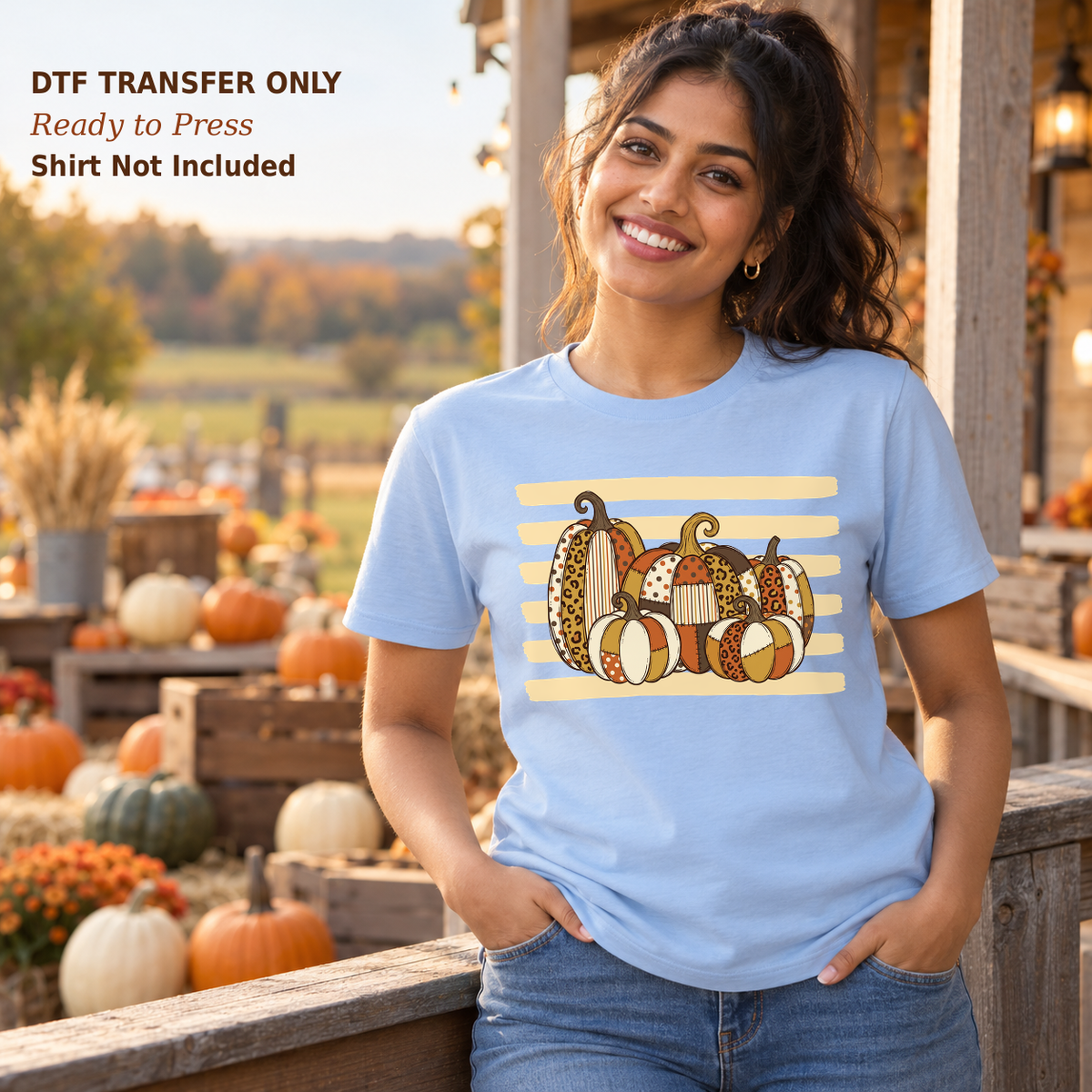 Woman in a light blue shirt with patterned fall pumpkins over pale horizontal stripes on an autumn porch.