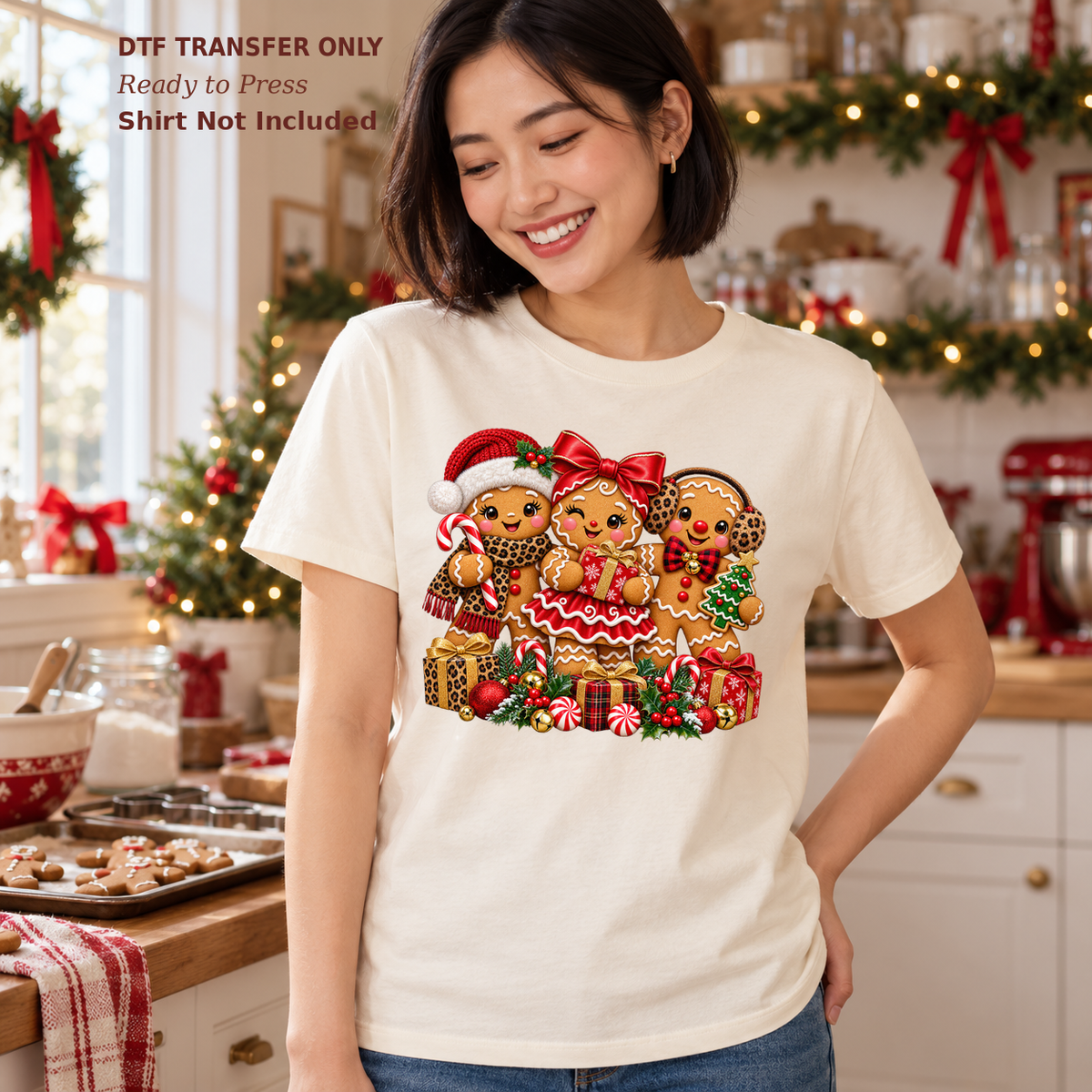 Woman wearing a white shirt with three decorated Christmas gingerbread characters and holiday sweets in a festive kitchen.
