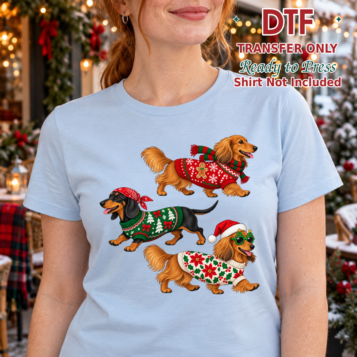Woman in a light blue tee with three dachshunds wearing Christmas sweaters and accessories.
