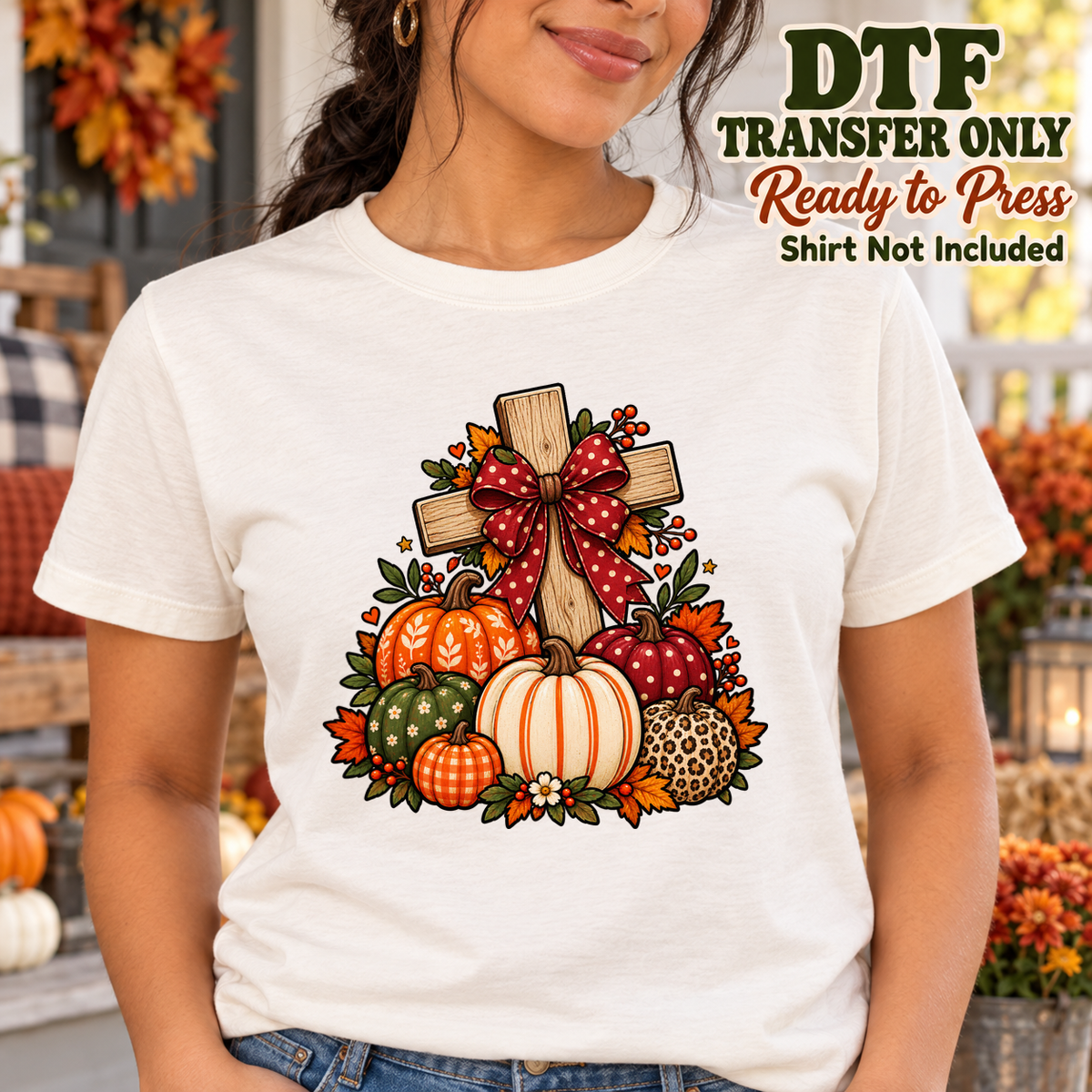 Woman in a cream tee with a wooden cross, red bow, pumpkins and fall foliage.
