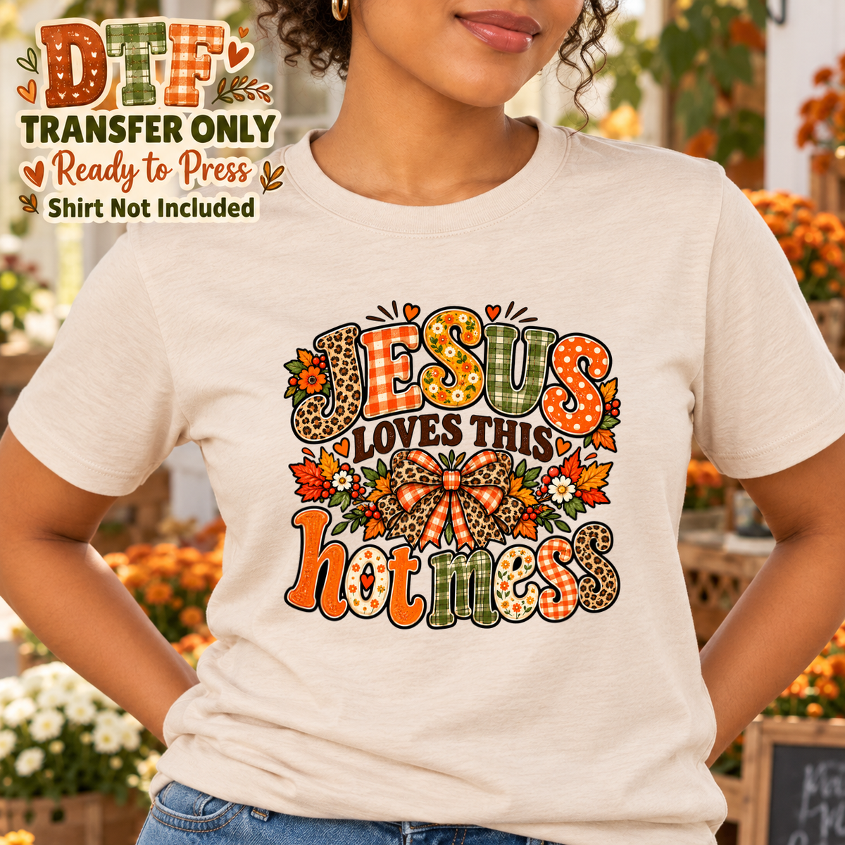 Woman in a cream tee with Jesus Loves This Hot Mess lettering and autumn flowers.