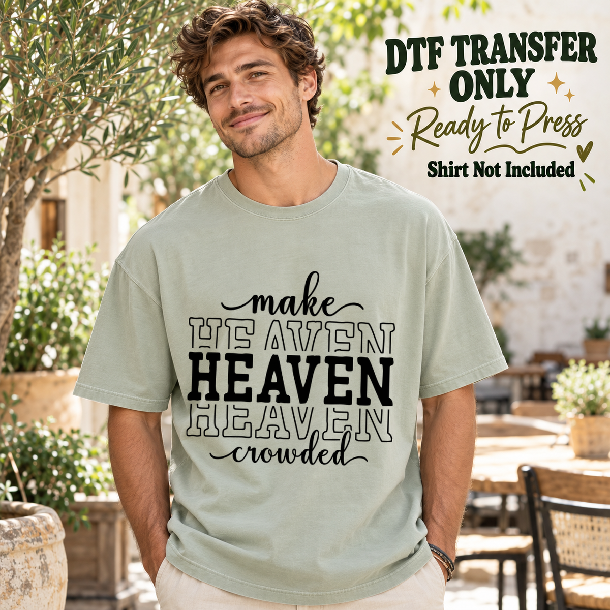 Man in a sage green tee displaying black Make Heaven Crowded text with repeated stacked solid and outline Heaven lettering, labeled transfer only.