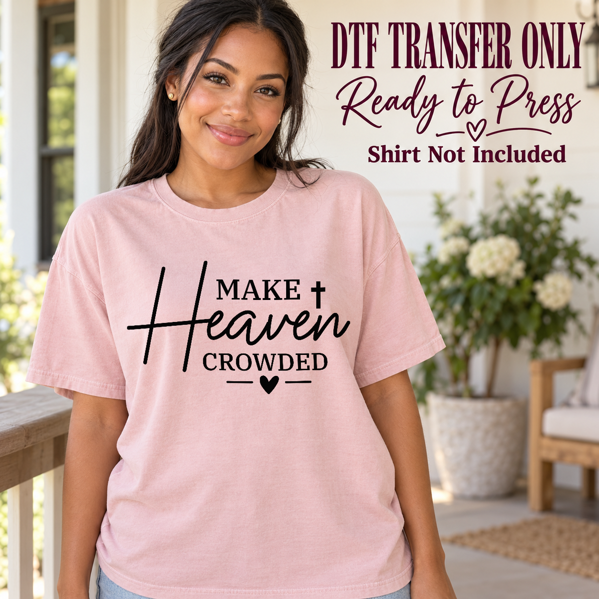 Woman in a pink tee with black Make Heaven Crowded lettering, sweeping script, a cross and small heart, labeled transfer only.