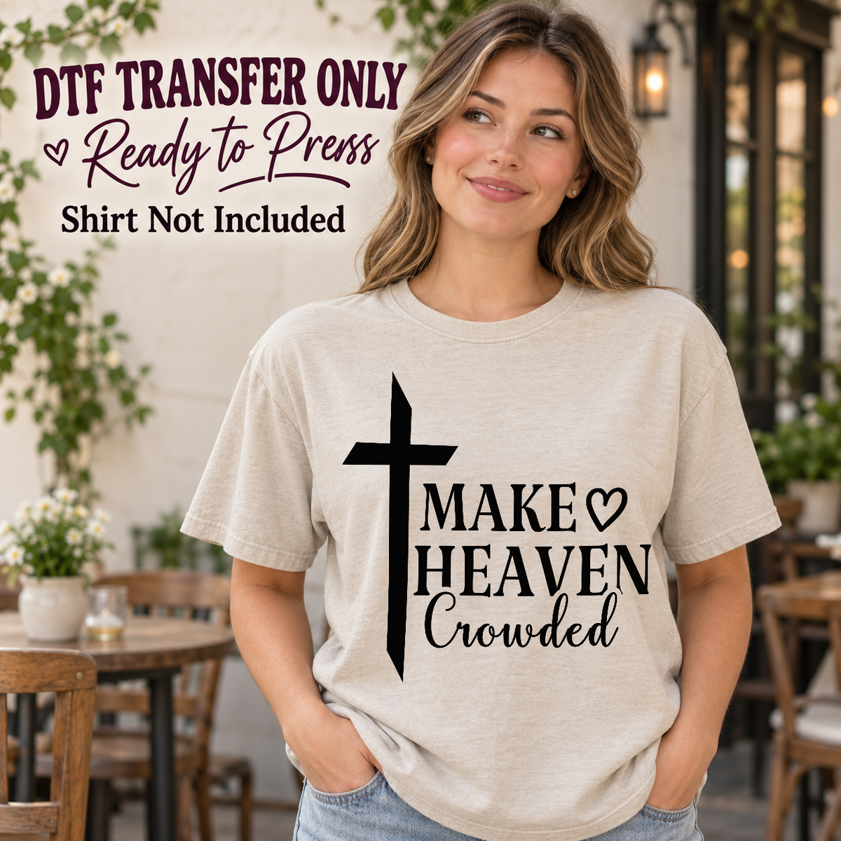 Woman in an ivory tee displaying a tall black cross next to Make Heaven Crowded text and an outlined heart, labeled transfer only.