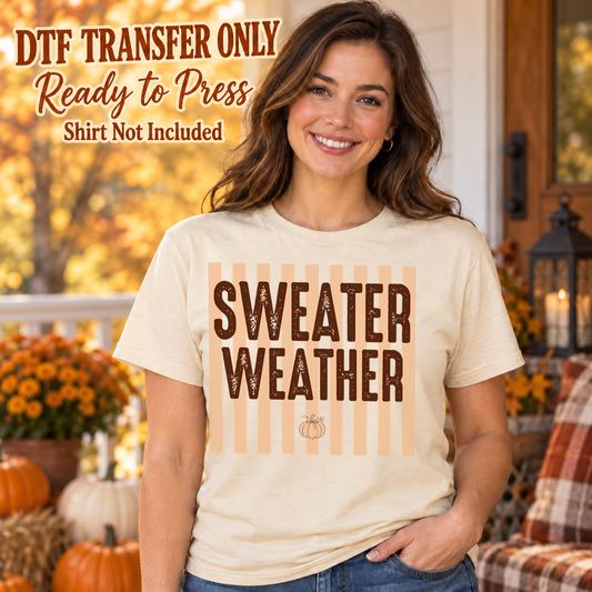 Woman in a cream tee displaying dark Sweater Weather block lettering over pale orange stripes and a small pumpkin, labeled transfer only.