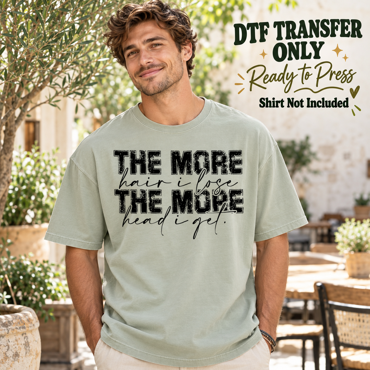 Man in a sage green tee with black The More Hair I Lose the More Head I Get lettering in mixed script and print, labeled transfer only.