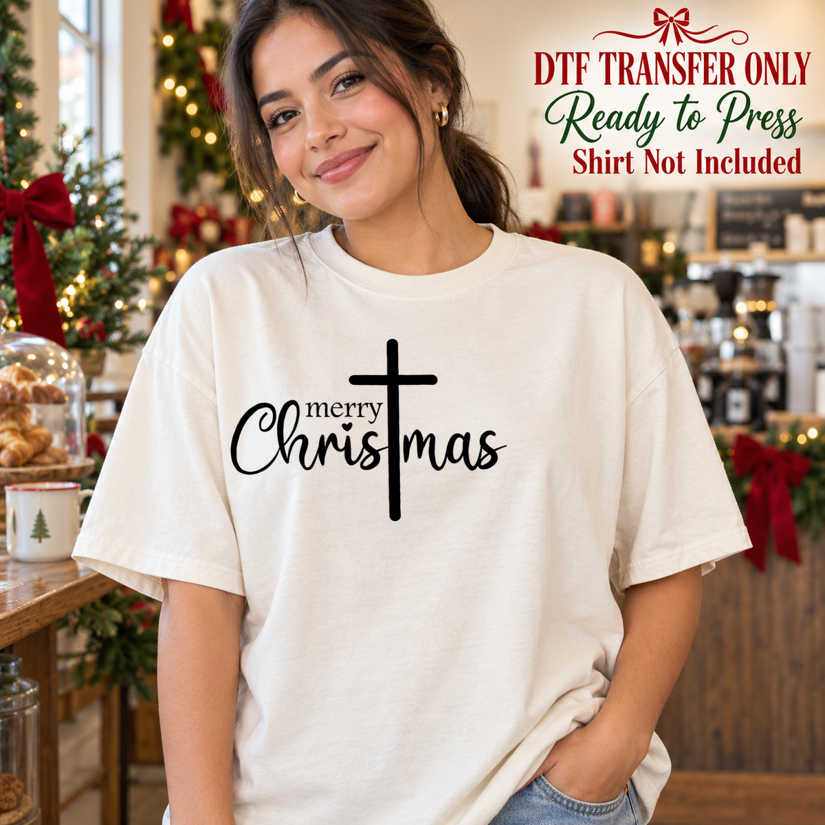 Woman in an ivory tee with black Merry Christmas script integrated with a tall cross, labeled DTF transfer only.