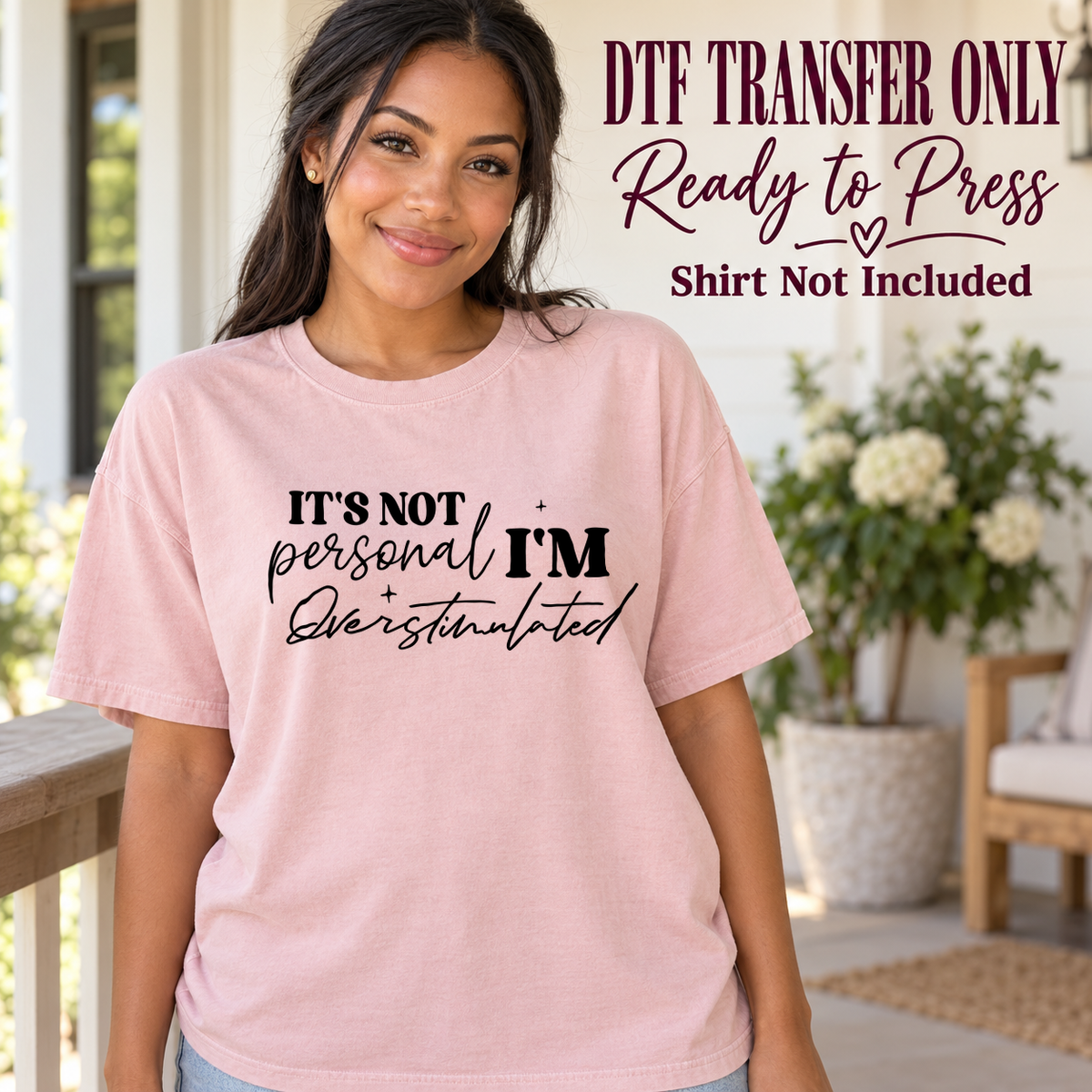 Woman in a pink tee with black It's Not Personal I'm Overstimulated lettering in mixed script and print, labeled DTF transfer only.