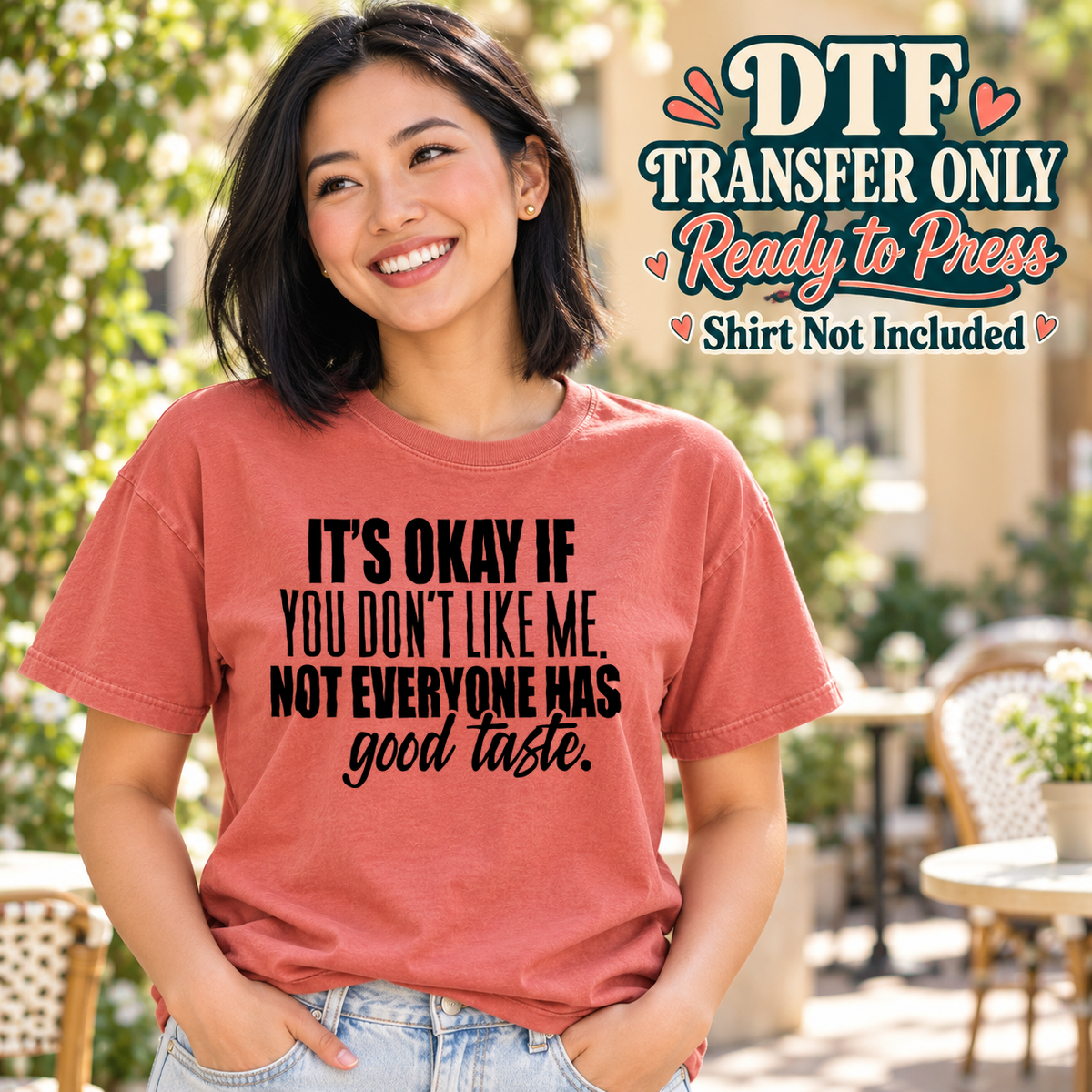 Woman in a coral tee showing It's Okay If You Don't Like Me Not Everyone Has Good Taste in black lettering, labeled transfer only.