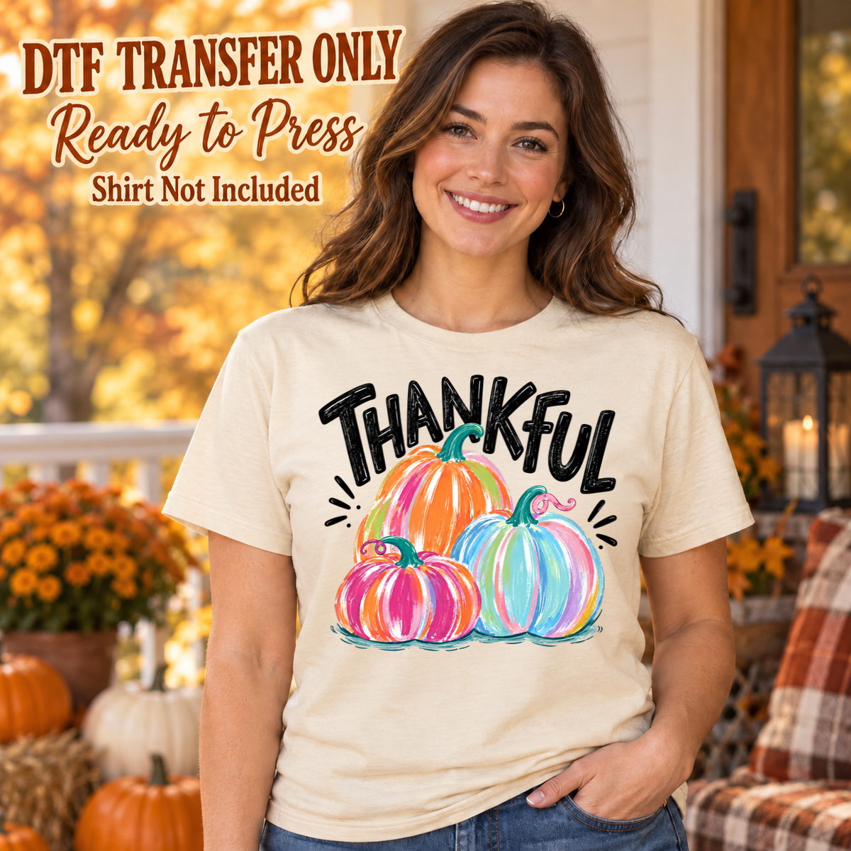 Woman in an ivory tee with black Thankful lettering above three brightly colored pink, orange and blue pumpkins, labeled transfer only.