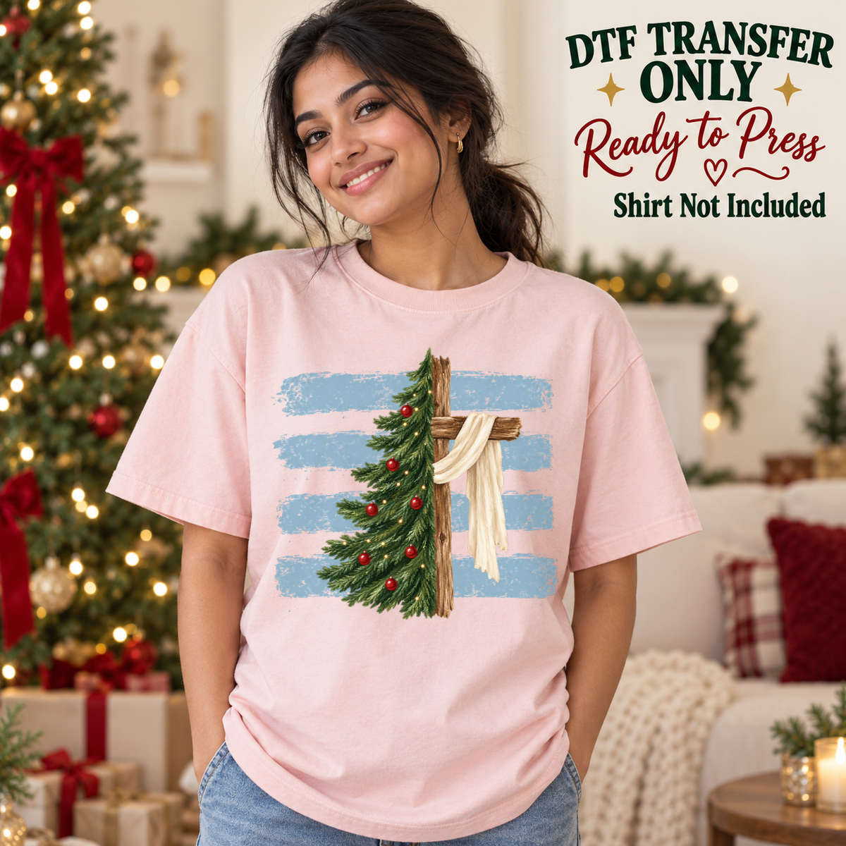 Woman in a pink tee displaying a decorated Christmas tree beside a draped wooden cross over blue brushstroke stripes, labeled transfer only.