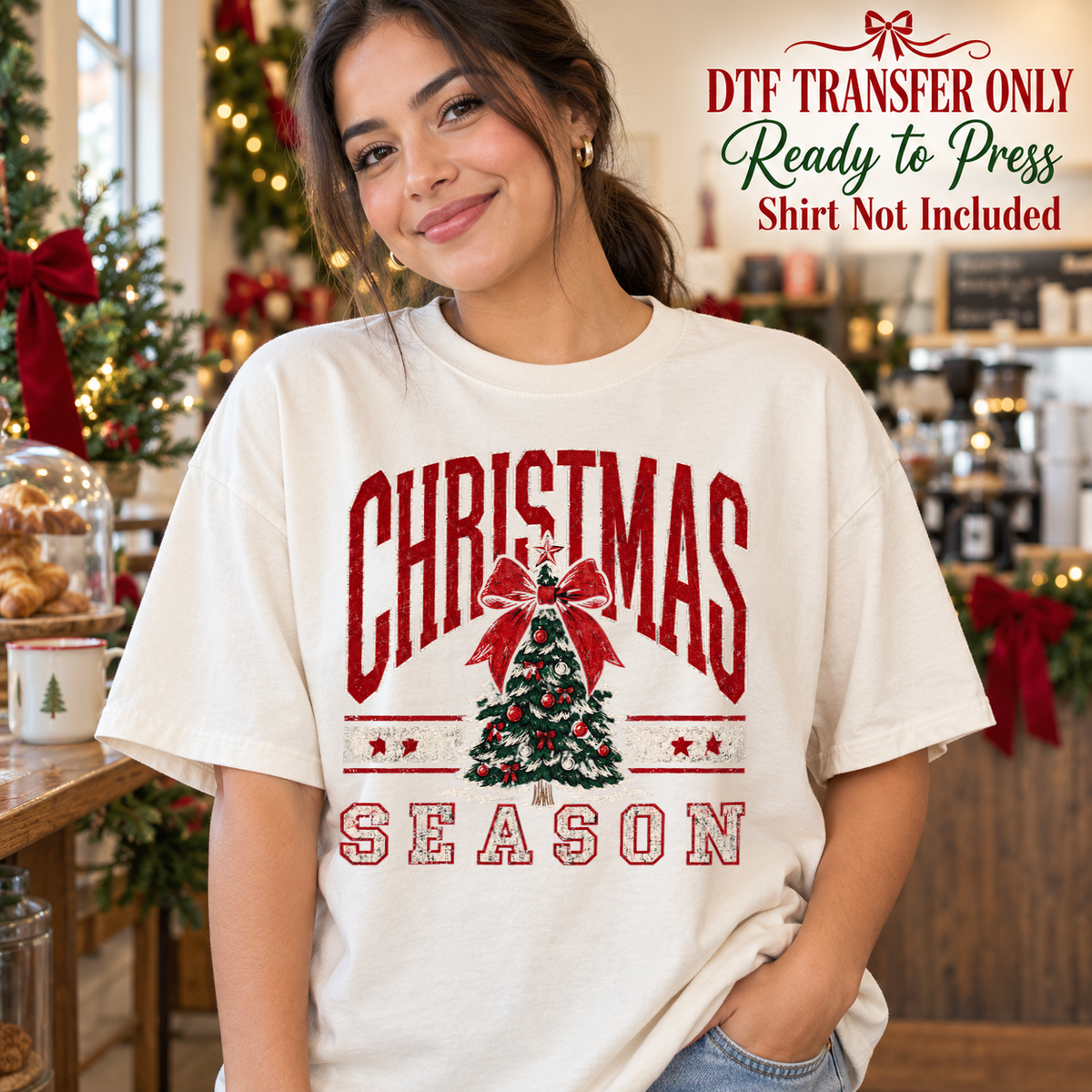 Woman in a white tee with red Christmas Season varsity lettering around a decorated tree topped with a bow, labeled DTF transfer only.