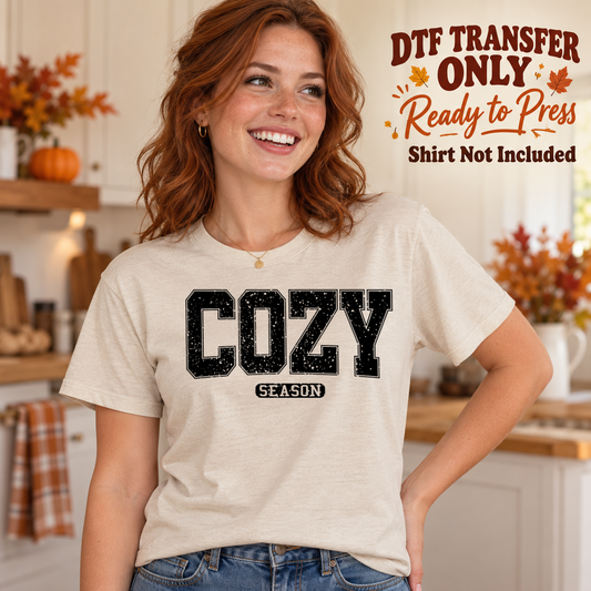 Woman in an ivory tee with large black varsity-style Cozy lettering above a small Season label, marked DTF transfer only.