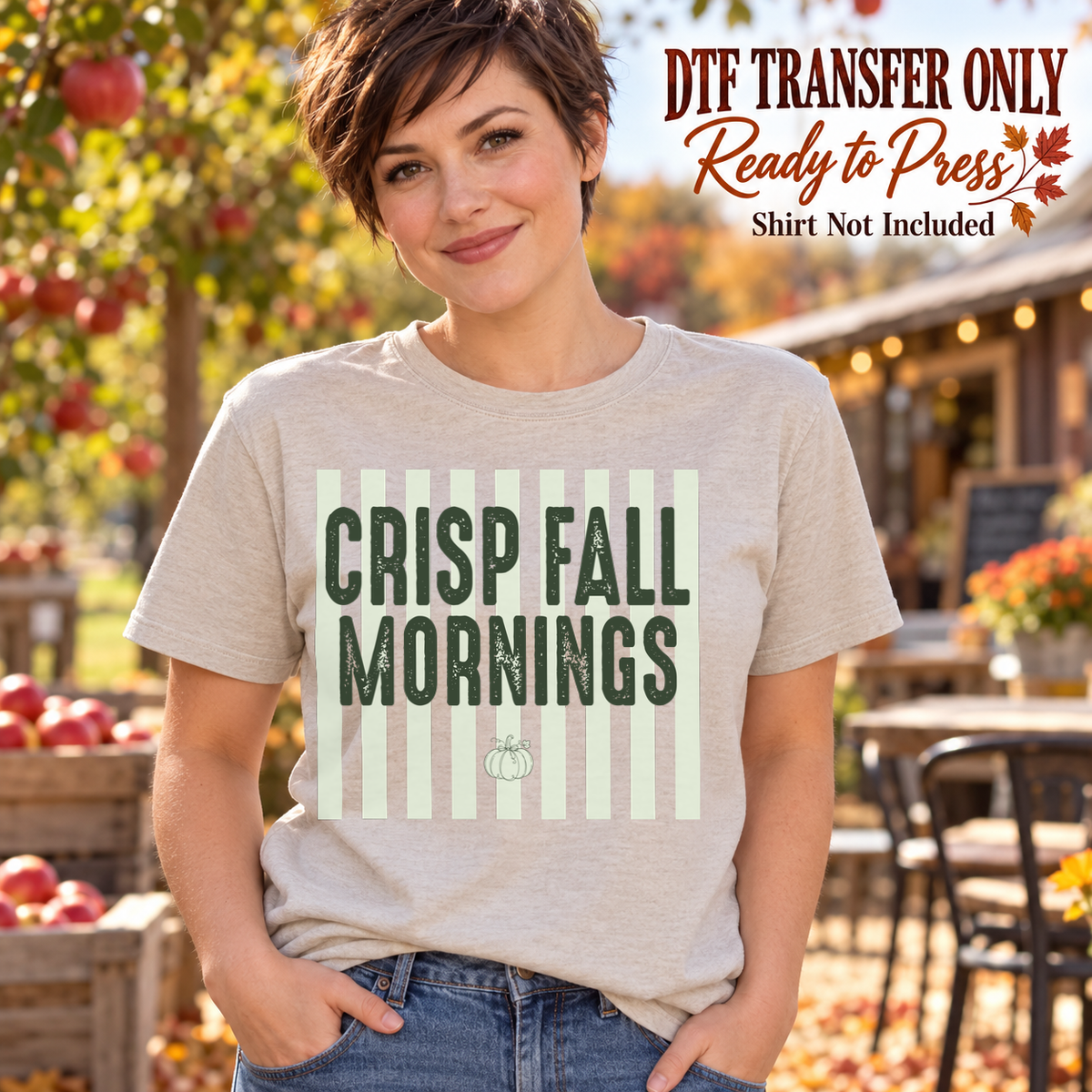 Woman in a light gray tee with green Crisp Fall Mornings block lettering over pale sage stripes and a small pumpkin, labeled transfer only.