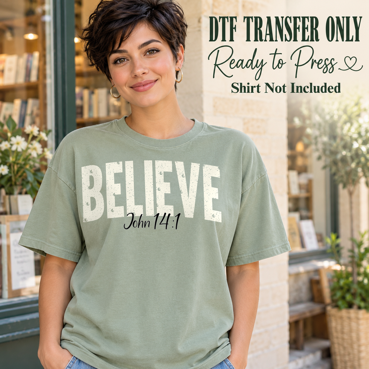Cream BELIEVE lettering with John 14:1 script beneath, shown on a sage green shirt model mockup; physical DTF transfer only, shirt not included.
