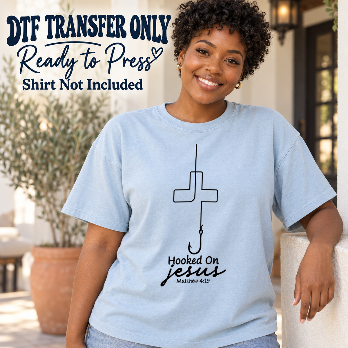 Black fishing-line cross above Hooked On Jesus text, shown on a light blue shirt model mockup; physical DTF transfer only, shirt not included.