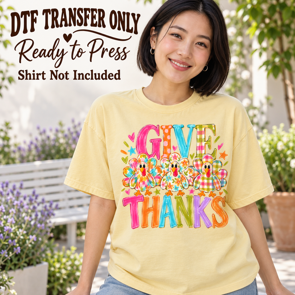 Colorful GIVE THANKS lettering with a band of bright flowers, shown on a pale yellow shirt model mockup; physical DTF transfer only, shirt not included.