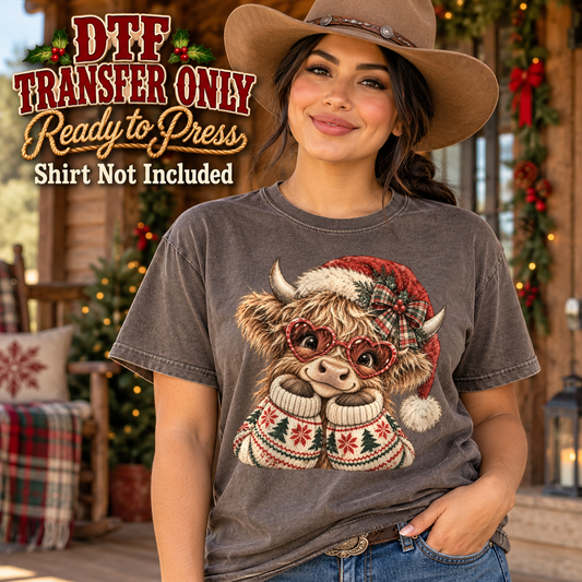 Highland cow with red glasses, Santa hat and patterned winter sweater, shown on a charcoal shirt model mockup; physical DTF transfer only, shirt not included.