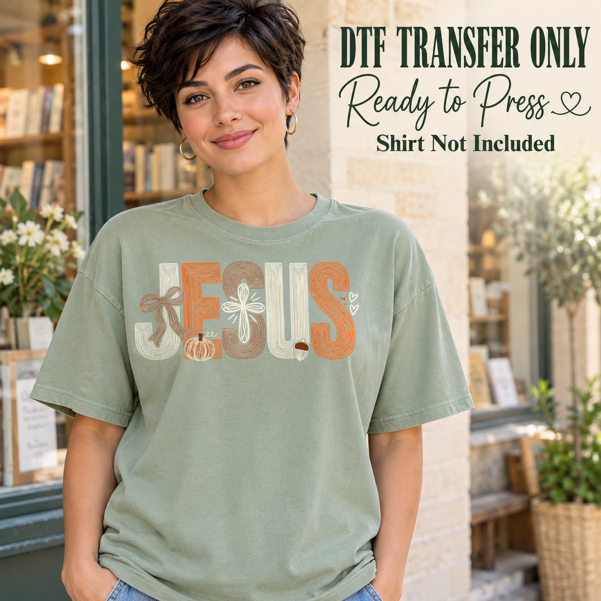 Cream and orange JESUS lettering with bow, cross and pumpkin details, shown on a sage green shirt model mockup; physical DTF transfer only, shirt not included.