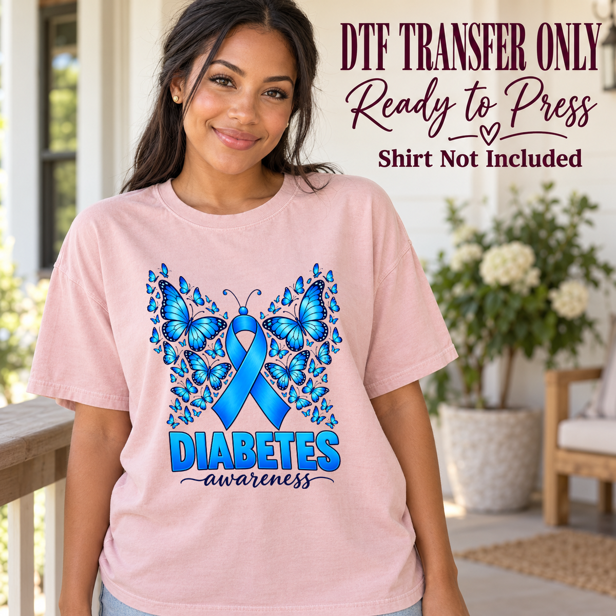 Model wearing a pink shirt showing blue awareness ribbon framed by blue butterflies and Diabetes Awareness text; DTF transfer only, shirt not included.
