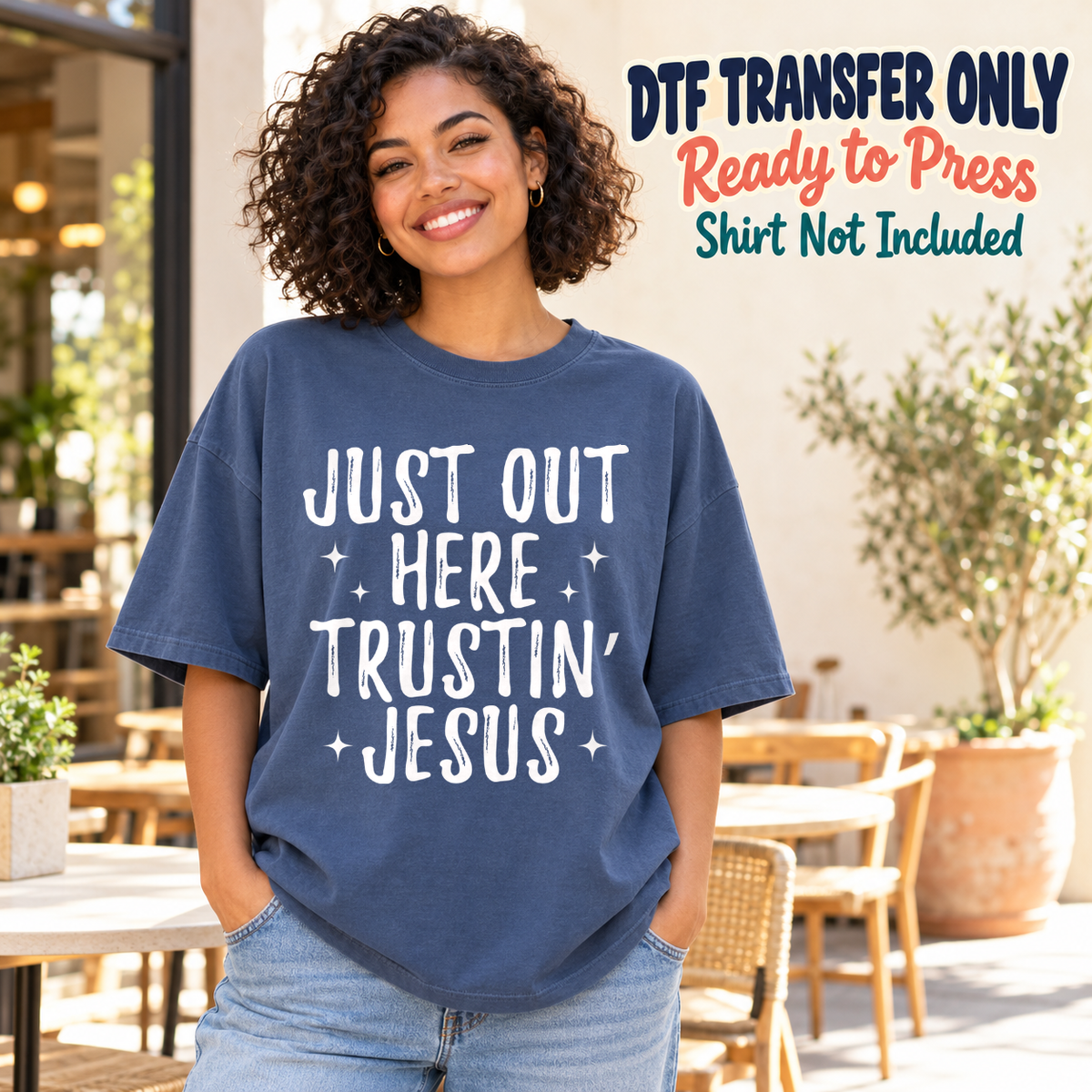 Model wearing a navy shirt showing Just Out Here Trustin’ Jesus in white lettering with stars; DTF transfer only, shirt not included.