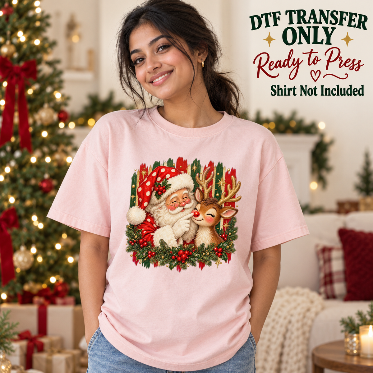 Model wearing a pink shirt with santa beside reindeer with holly and red hat; DTF transfer only, shirt not included.
