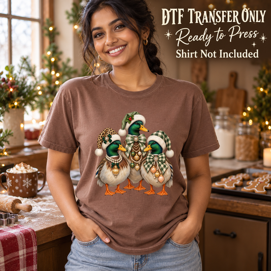 Model wearing a brown shirt with three ducks wearing christmas hats and festive accessories; DTF transfer only, shirt not included.