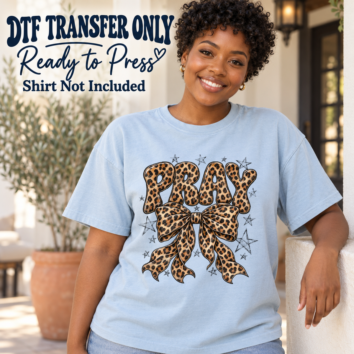 Model wearing a light blue shirt with pray leopard lettering with leopard bow and stars; DTF transfer only, shirt not included.