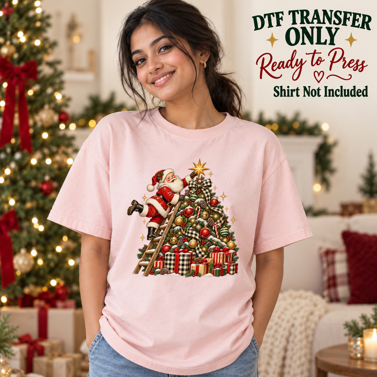 Santa on a ladder decorating a Christmas tree shown on a pink shirt worn by a woman; DTF transfer only, shirt not included.