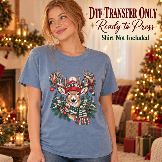 Reindeer in a knit hat with holiday ornaments and greenery shown on a blue shirt worn by a woman; DTF transfer only, shirt not included.