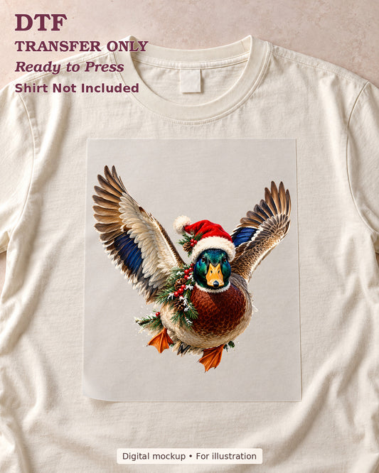 Flying mallard duck in a Santa hat with festive greenery, shown as a transfer sheet on a cream shirt; shirt not included.