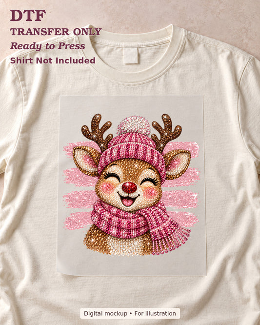 Smiling reindeer in a pink knit-look hat and scarf DTF transfer shown on film over a cream shirt; shirt not included.