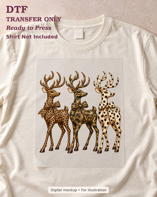 Three antlered deer in leopard, camouflage and spotted patterns with neck bows shown as a transfer sheet on a cream shirt; shirt not included.