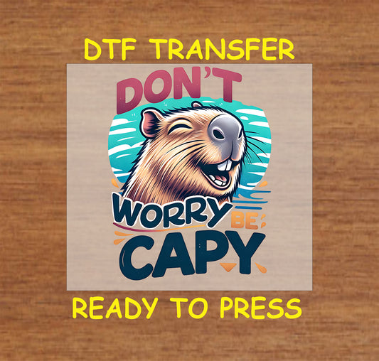 Don’t Worry Be Capy DTF transfer showing a cheerful capybara with a vibrant, sunny background and bold, colorful text.