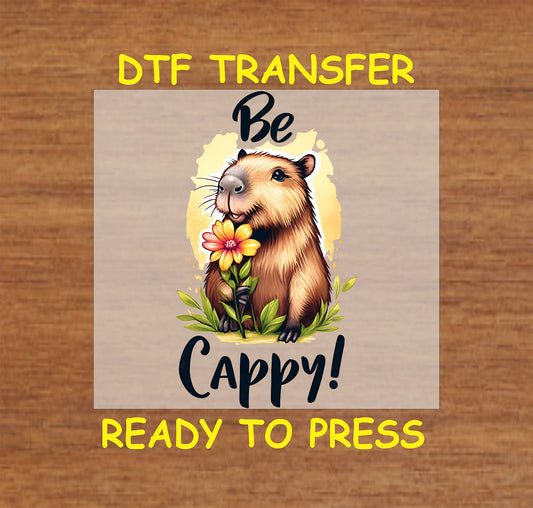 "Be Cappy" DTF transfer with a cheerful capybara holding a flower and yellow background.