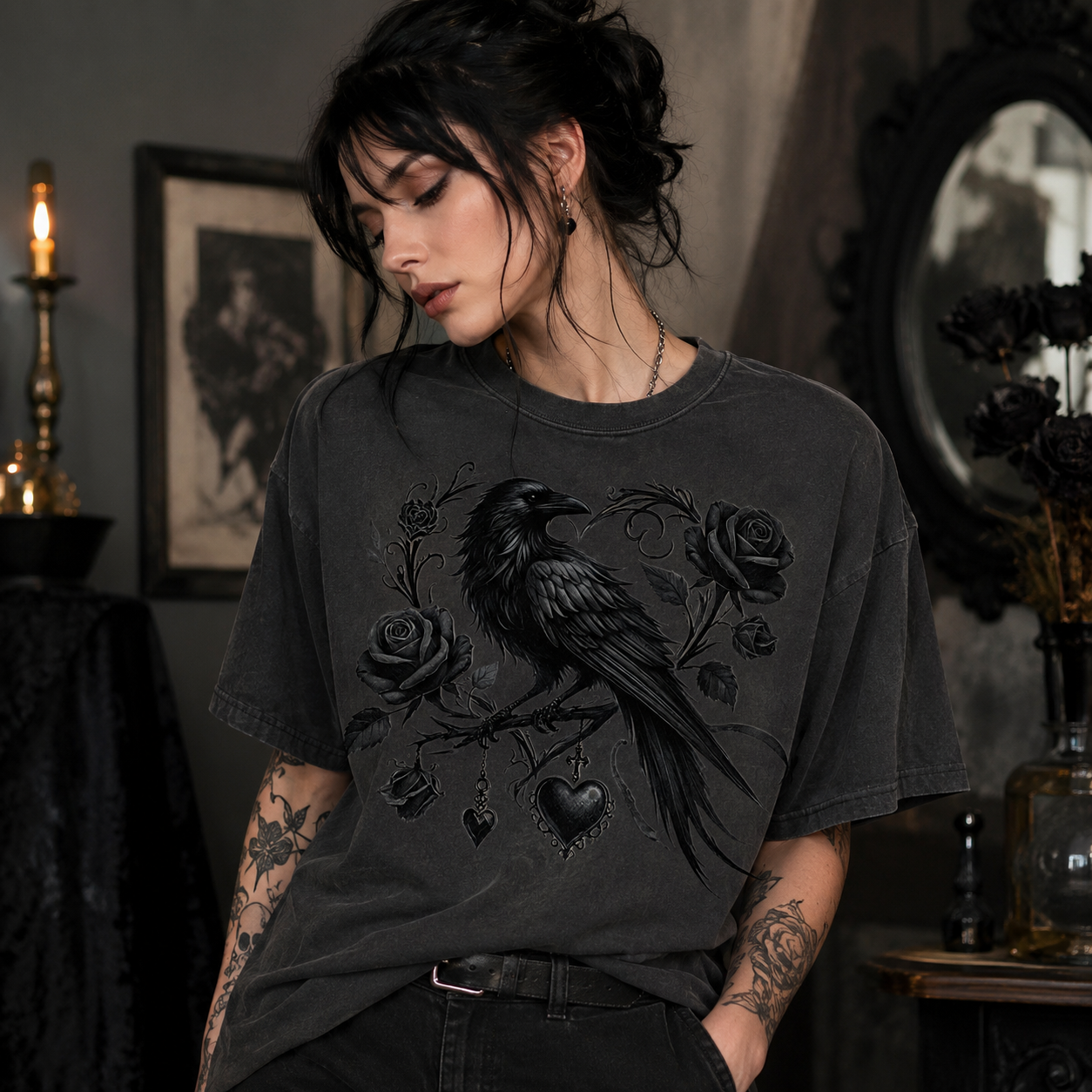 A woman wearing a dark charcoal gray t-shirt with a black graphic of a raven perched on a rose branch with hearts, set in a dark, gothic-themed room.