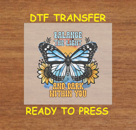 "DTF transfer featuring a butterfly with blue wings, sunflowers, and the phrase 'Balance the Light and Dark Within You.'"