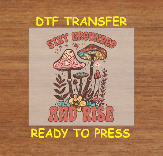"DTF transfer featuring mushrooms, flowers, and the phrase 'Stay Grounded and Rise' in retro-style lettering."