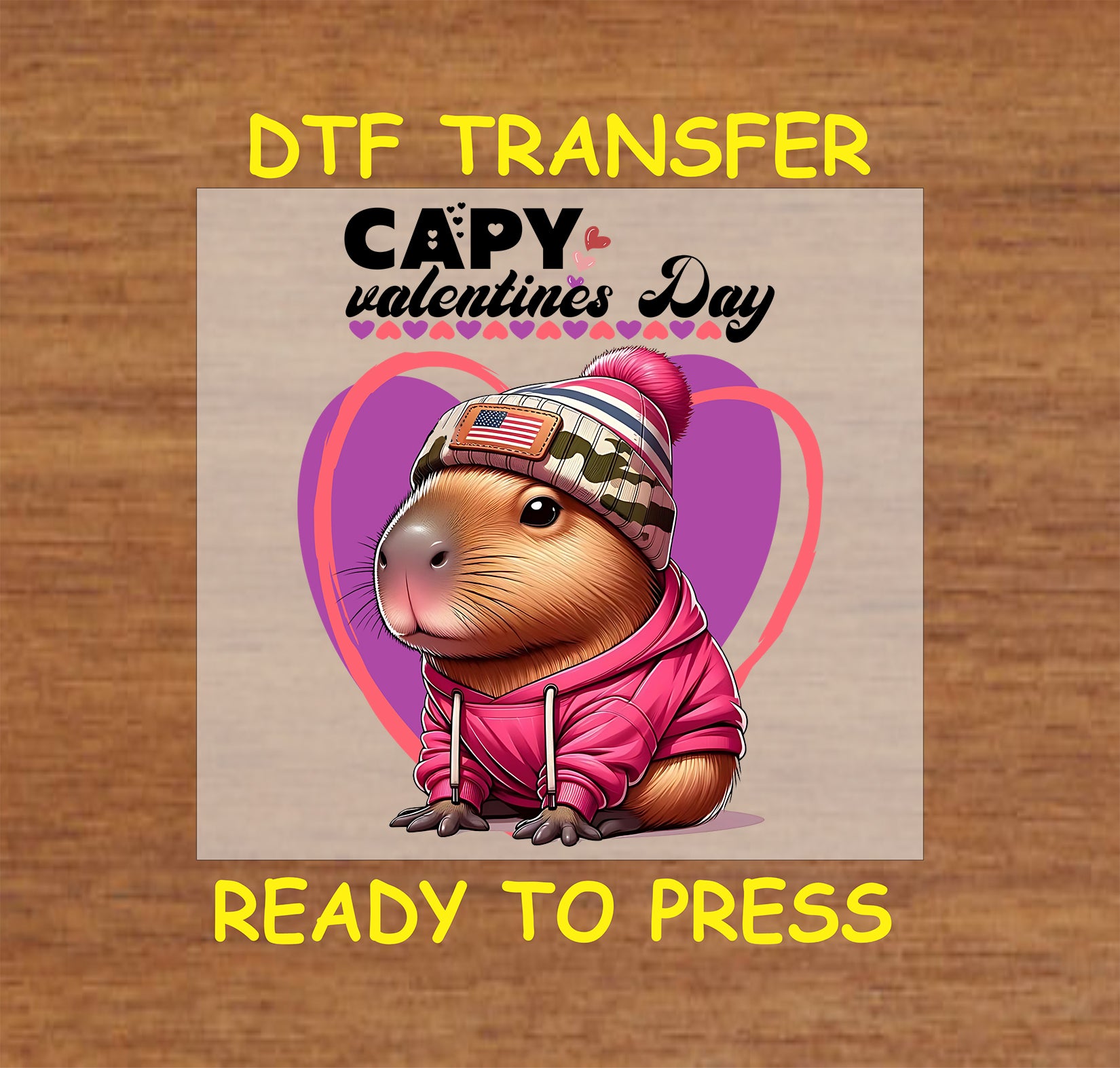 "DTF transfer featuring a capybara in a pink hoodie and camo beanie with an American flag patch, against a purple Valentine's Day heart background."