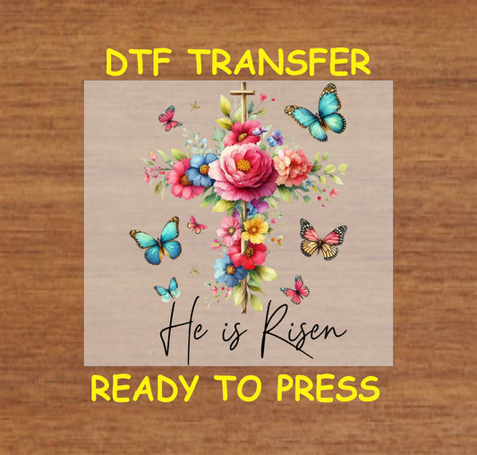He Is Risen DTF transfer with a gold cross, colorful flowers, and butterflies.
