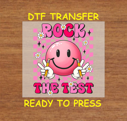 Rock the Test DTF transfer with a pink smiley face, peace signs, pencils, and a checkered background.