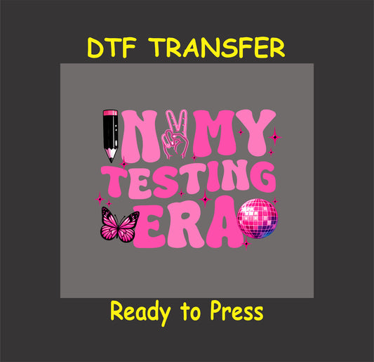 In My Testing Era DTF transfer with pink aesthetic lettering, a pencil, peace sign, butterfly, and disco ball.