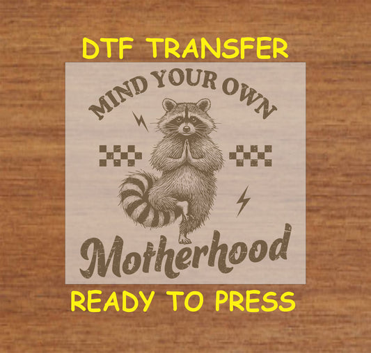 Mind Your Own Motherhood DTF transfer with a meditating raccoon, retro checkers, and lightning bolts.