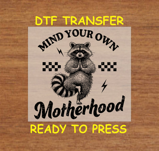 Mind Your Own Motherhood DTF transfer with a meditating raccoon, checkered pattern, and lightning bolts in a vintage style.
